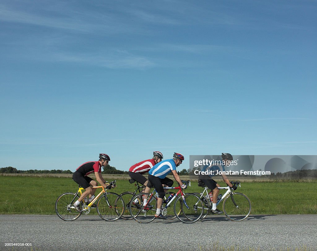 Mature men cycling racing bikes on road, side view