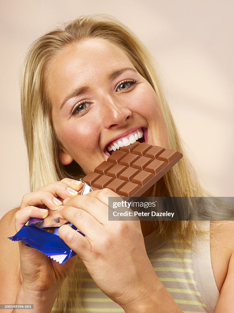 Young woman eating chocolate, close-up, portrait