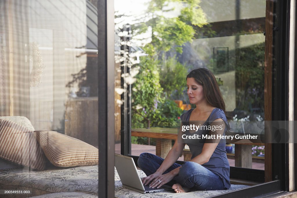 Woman using laptop by window