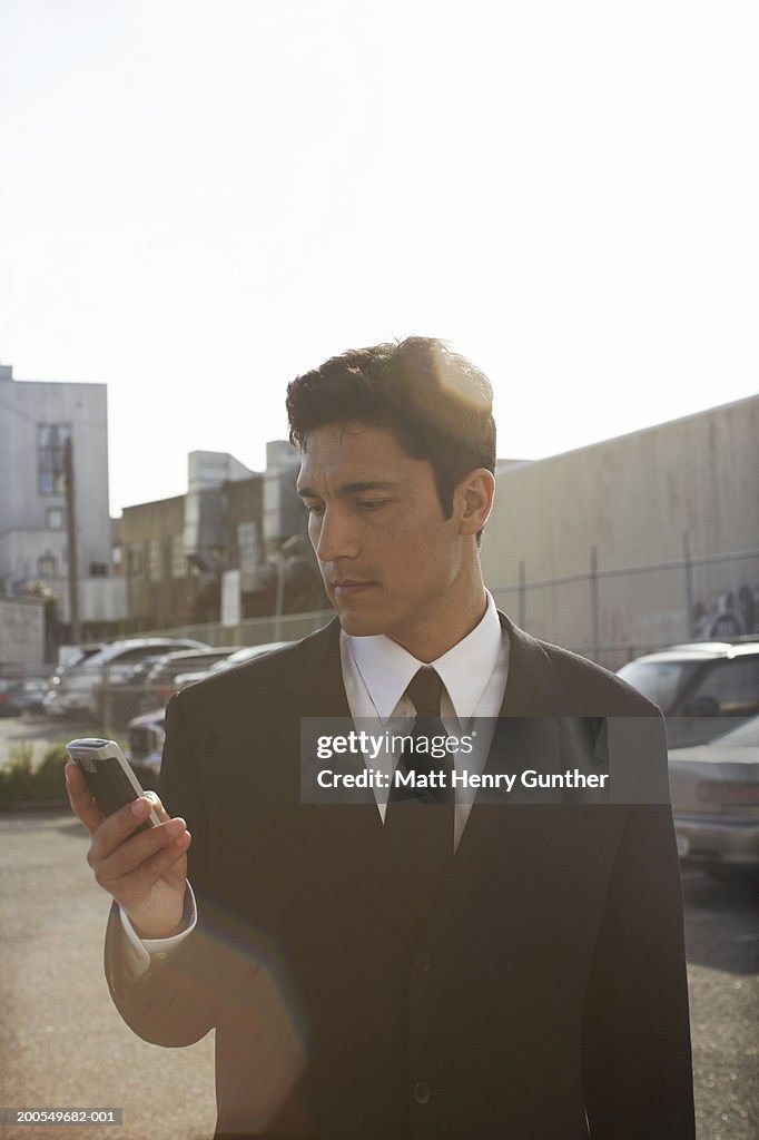 Businessman using mobile phone in parking lot