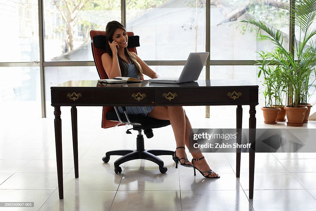 Young businesswoman at desk using mobile phone