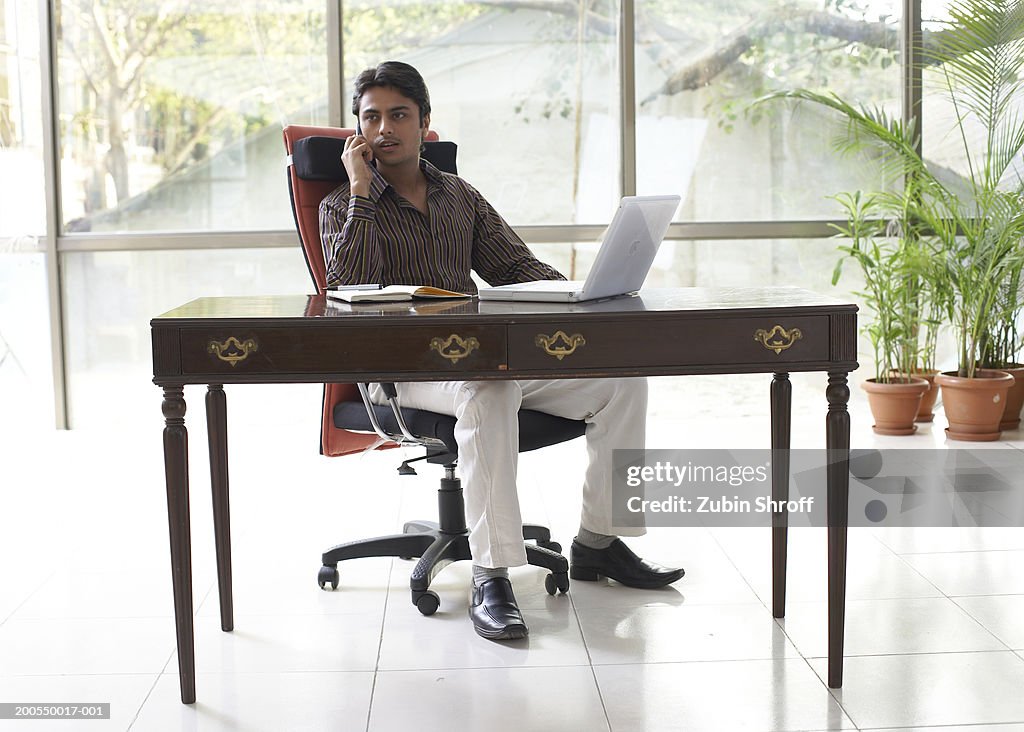 Young businessman working, using mobile phone