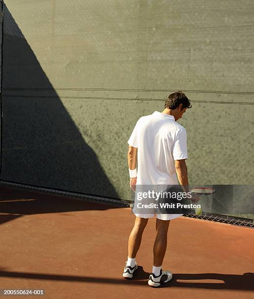 man bouncing tennis ball on court, rear view - bounce stock-fotos und bilder