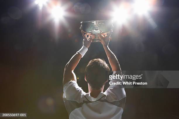tennis player holding winner's cup, rear view - match sport stock-fotos und bilder