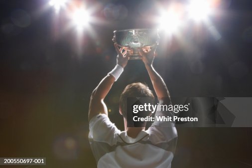 Tennis player holding winner's cup, rear view Tennis player holding winner's cup, rear view