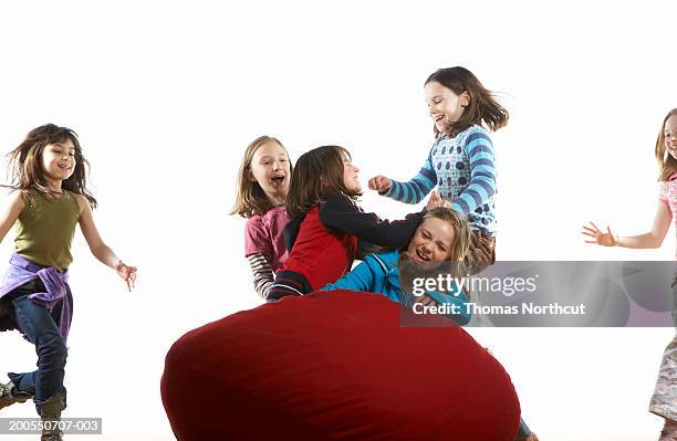 six girls (8-10) roughhousing on bean bag, laughing - rough housing stock pictures, royalty-free photos & images