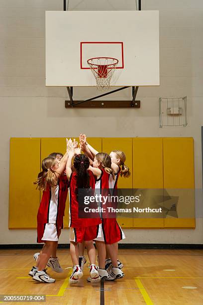 group of girls (8-10) cheering and high-fiving on basketball court - basketball team stock pictures, royalty-free photos & images