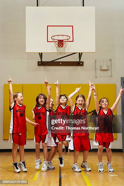 group of girls (8-10) cheering on basketball court, arms raised - basket sport stock pictures, royalty-free photos & images