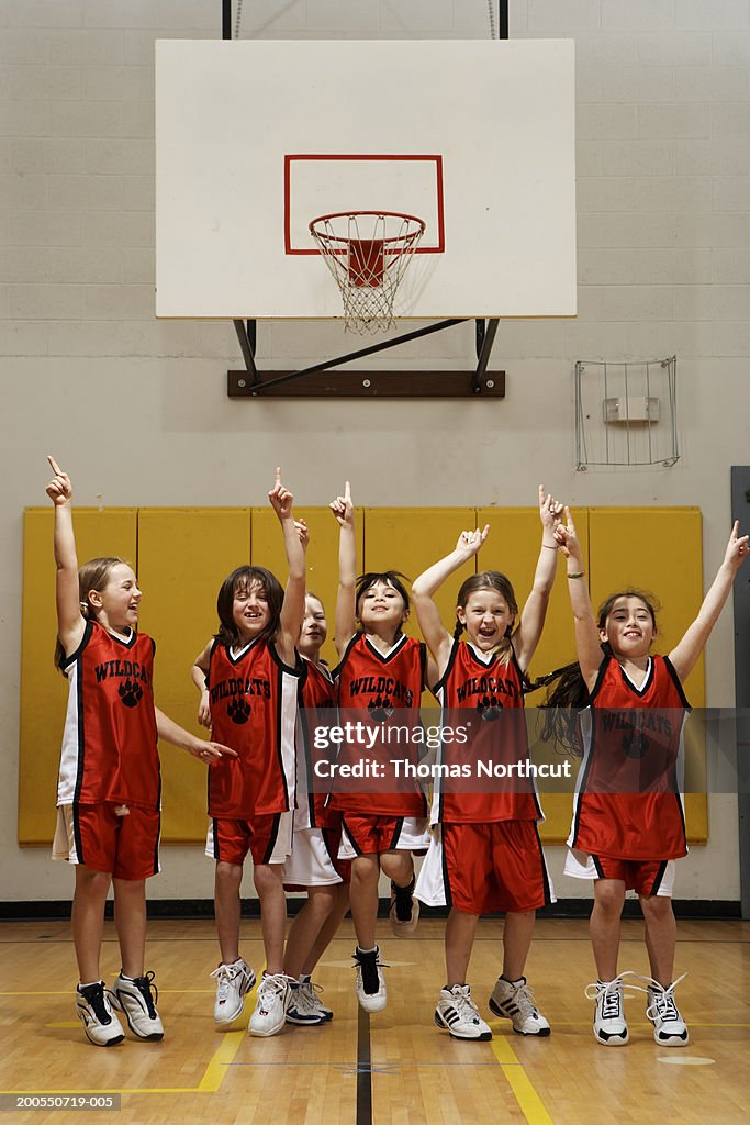Group of girls (8-10) cheering on basketball court, arms raised