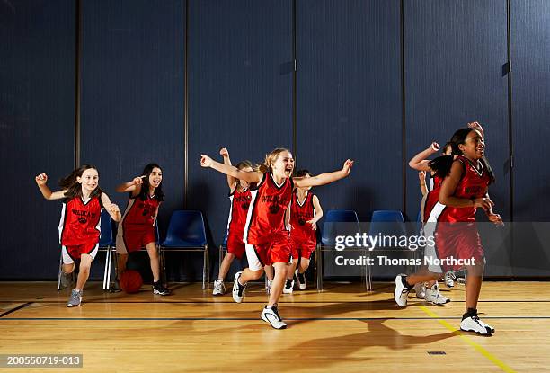 girls (8-10) running onto basketball court, cheering - girls basketball team stock pictures, royalty-free photos & images