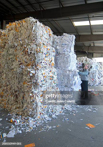 man standing by stack of recycled paper, side view - paper industry stock-fotos und bilder