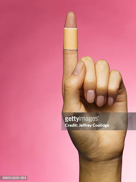 young woman holding up bandaged finger - human finger stock pictures, royalty-free photos & images