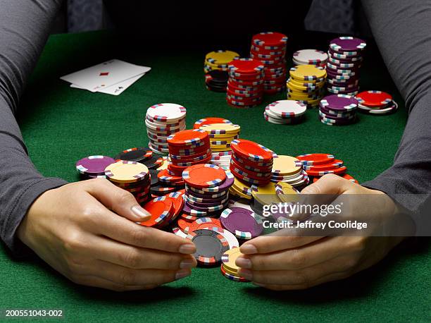 young woman scooping up large pile of poker chips - poker stockfoto's en -beelden