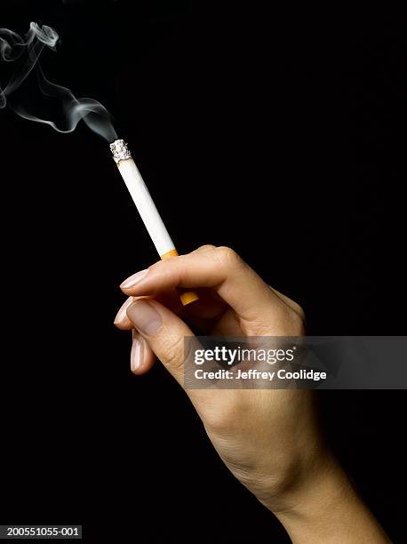 young woman holding burning cigarette - sigaretta foto e immagini stock