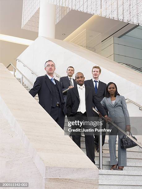 businesspeople standing on stairway, smiling, portrait, low angle view - group of businesspeople standing low angle view stock pictures, royalty-free photos & images