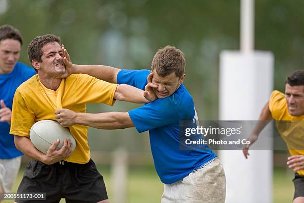 young rugby players grappling for ball - aanvallen sporten stockfoto's en -beelden