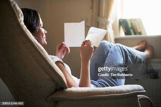 young woman reading letter and smiling - thinking of you card - fotografias e filmes do acervo