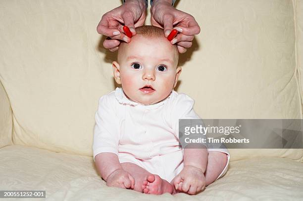 baby girl (3-6 months) with hand placing candy on head - disfraz de diablo fotografías e imágenes de stock