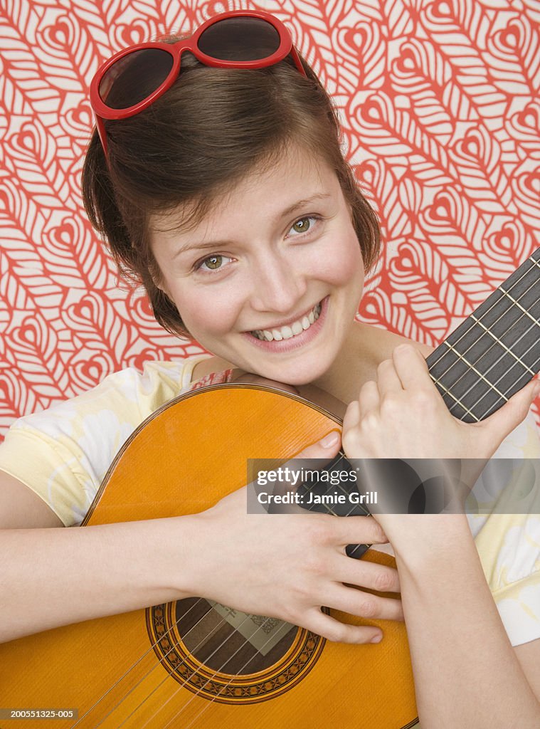 Young woman holding guitar, smiling, portrait