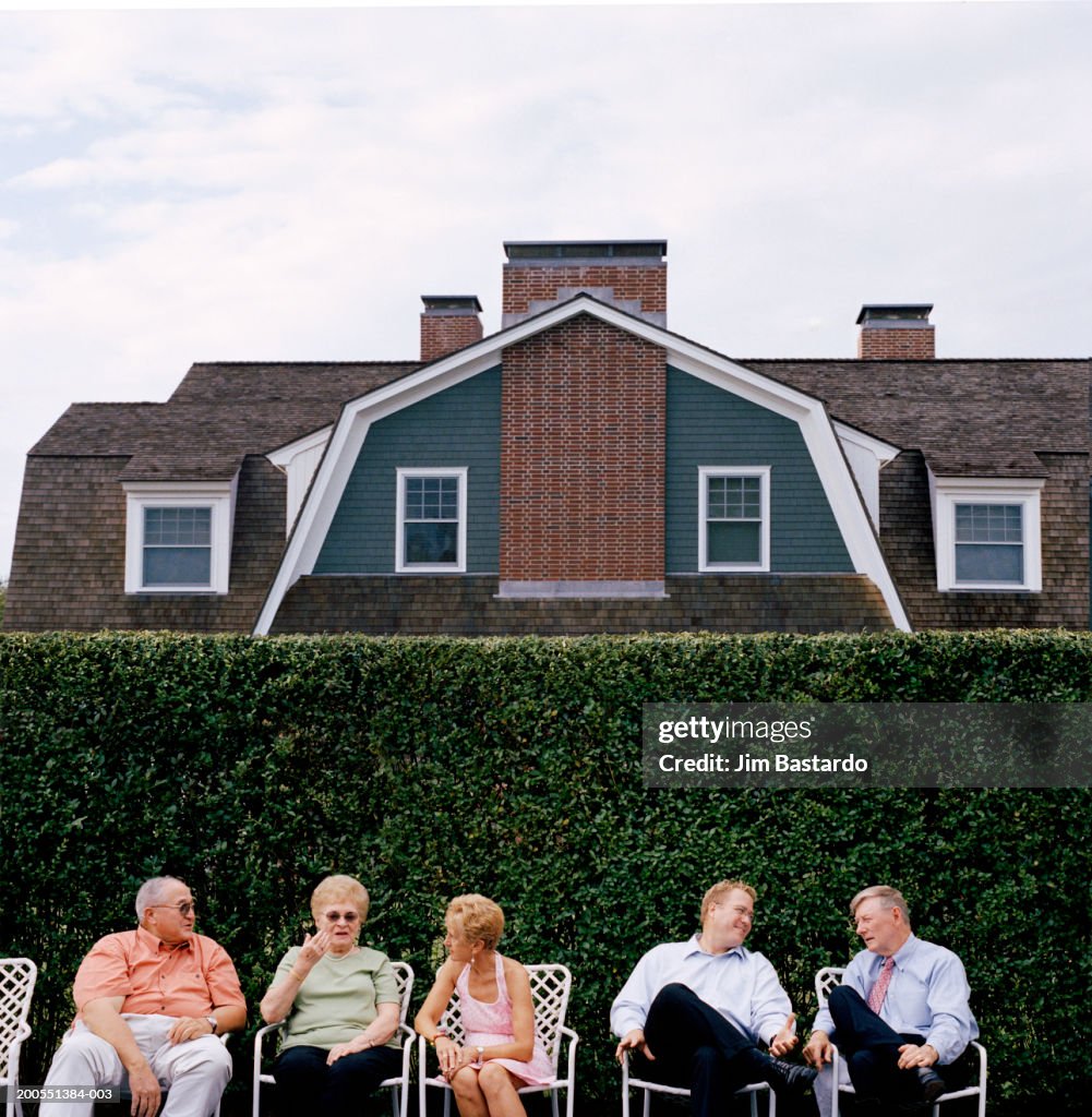 Five people sitting in row in front of house