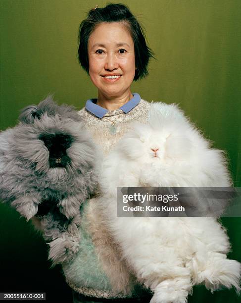 woman holding two angora rabbits, portrait, smiling - züchter stock-fotos und bilder