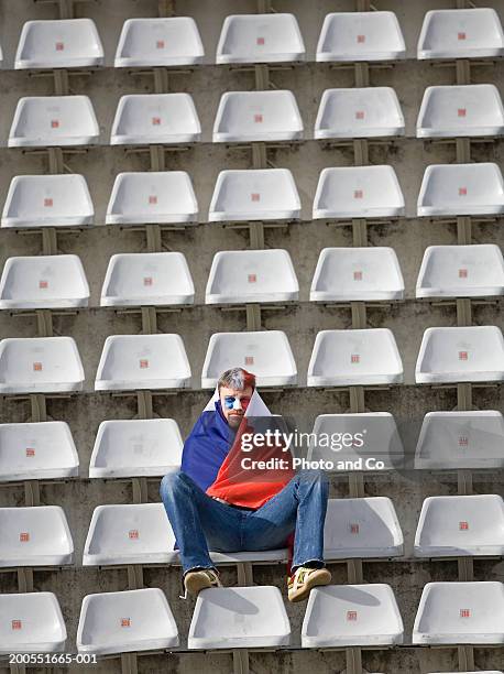 male rugby fan wrapped in french flag, sitting in stadium - overthrow stock pictures, royalty-free photos & images