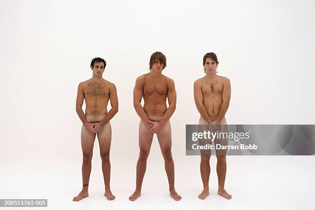 three naked young men standing in line, hands covering groin - birthday suit stock-fotos und bilder