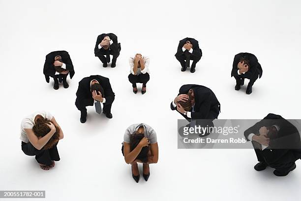 group of young businesspeople crouching, head in hands, elevated view - かがむ 人 横 ストックフォトと画像