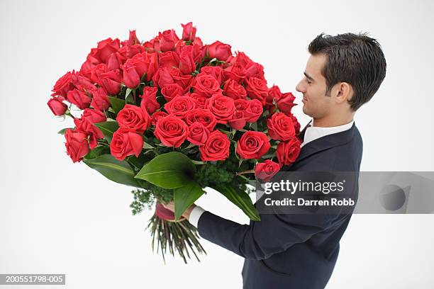 young businessman holding bouquet of red roses, side view - red roses stock pictures, royalty-free photos & images