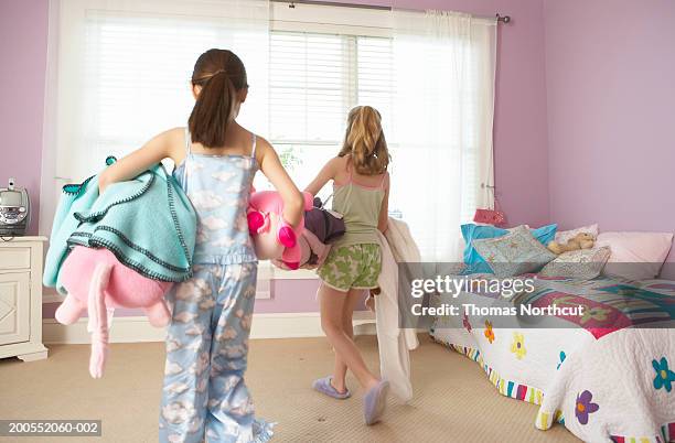 two girls (8-10) carrying blankets in bedroom, rear view - neat fotografías e imágenes de stock