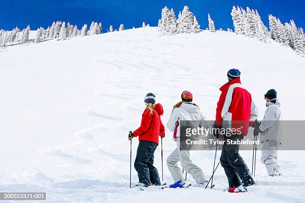 four skiers holding ski poles, looking at hill - calças para esquiar imagens e fotografias de stock