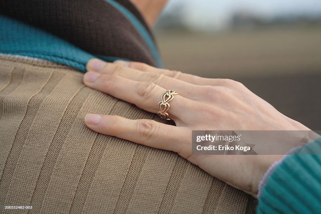 Woman's hand on man's shoulder, close-up, rear view