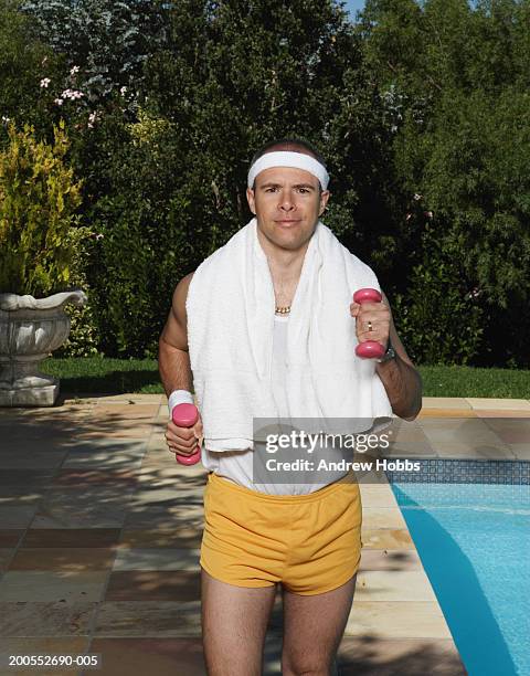 mature man jogging with dumbbells at poolside, portrait - sweat band stock pictures, royalty-free photos & images