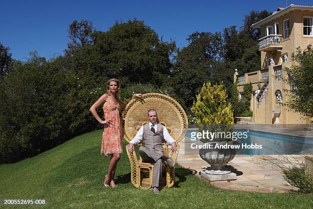 mature man sitting in armchair, woman standing, portrait - millionnaire stock pictures, royalty-free photos & images