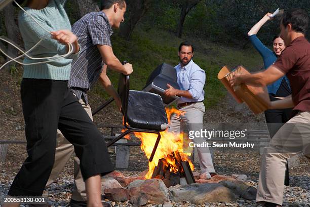 businessmen and woman throwing office supplies into bonfire - riot fire stock pictures, royalty-free photos & images
