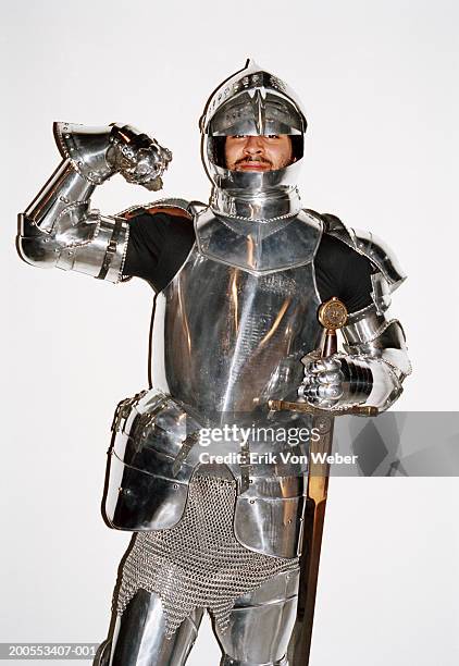 man in knight's armour costume flexing muscles against white background, portrait - armoured stockfoto's en -beelden