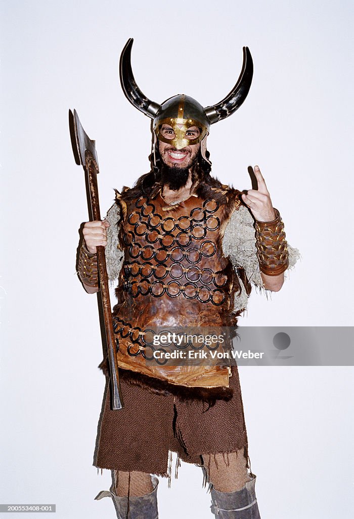 Young man in Viking costume against white background, smiling, portrait