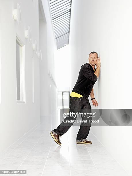 man listening at wall, side view - leaning stock pictures, royalty-free photos & images