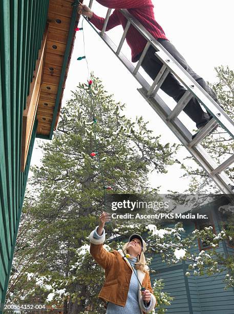 mature couple putting christmas decorations around house - versierd jak stockfoto's en -beelden