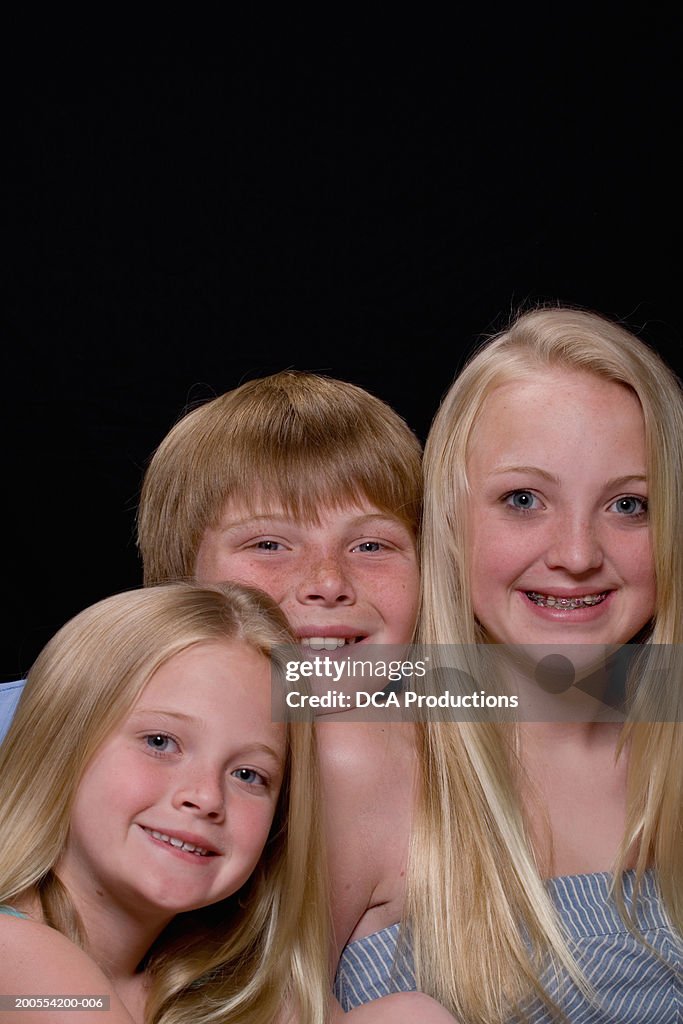 Teenage girl (13-14) with brother and sister (6-11), smiling, close-up, portrait