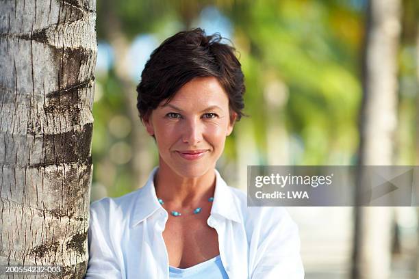 mature woman leaning on tree trunk, smiling, portrait - short trees bildbanksfoton och bilder