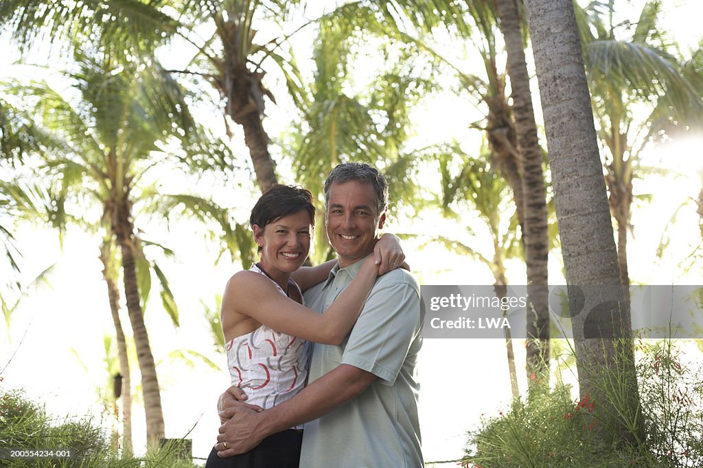 Couple embracing on beach, smiling, portrait