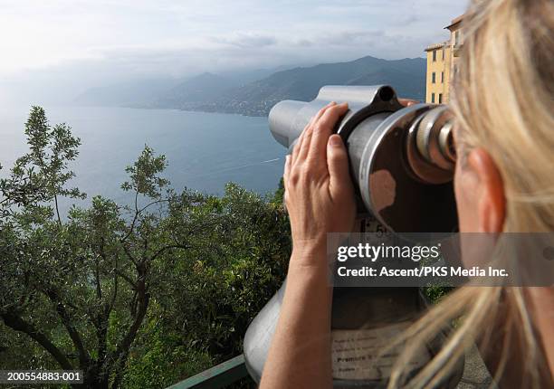 woman using telescope, viewing coastline - catalejo fotografías e imágenes de stock