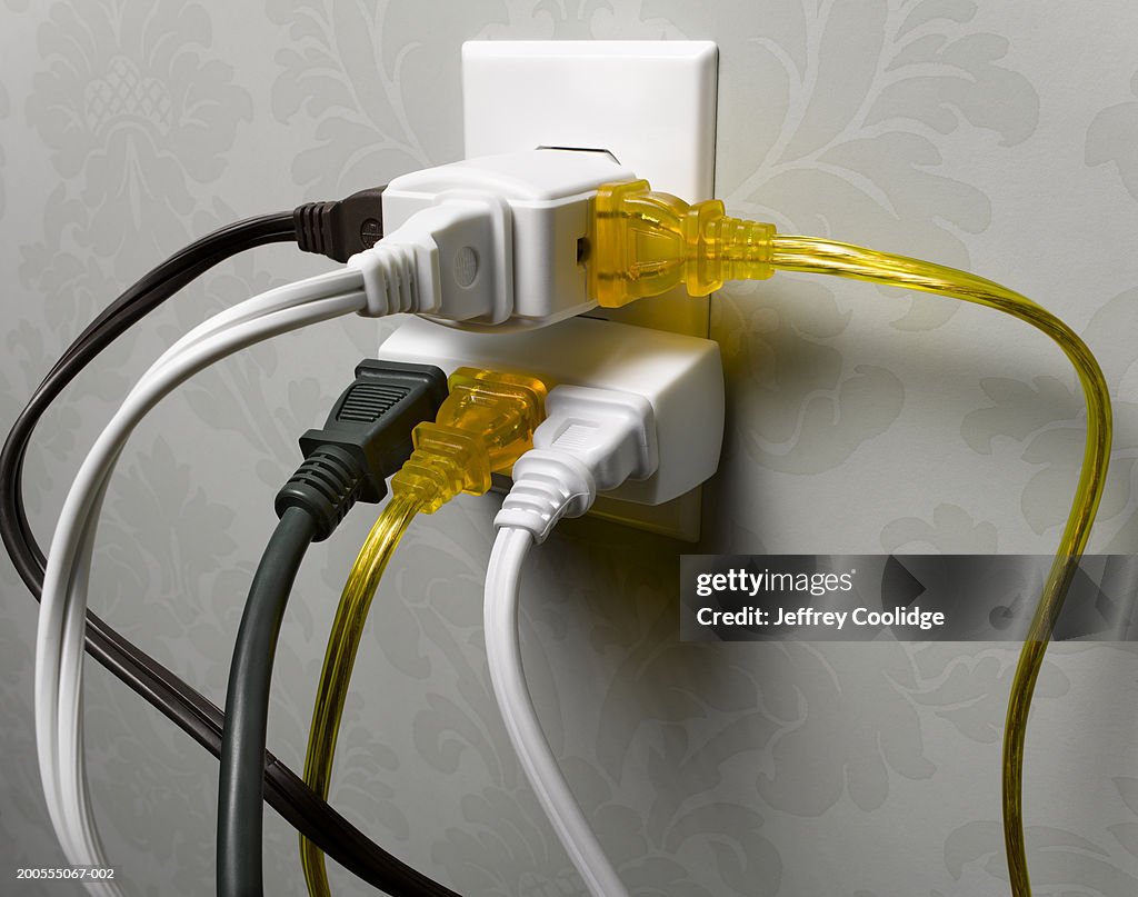 Electrical wall outlet overloaded with plugs, close-up