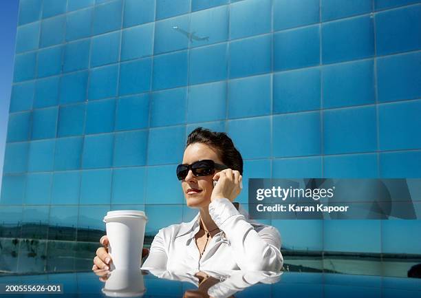 businesswoman using mobile phone with coffee on car roof - car roof stock pictures, royalty-free photos & images