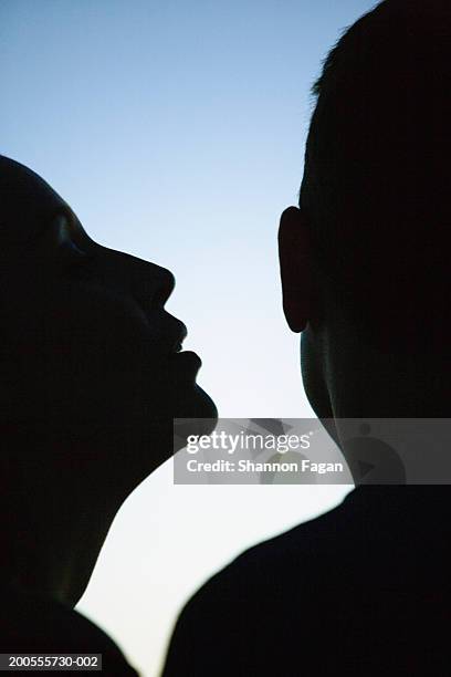 profile of woman whispering in man's ear in silhouette - human ear bildbanksfoton och bilder