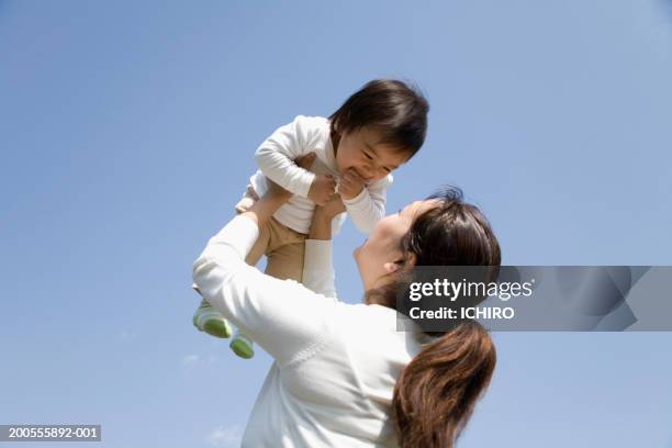 mother lifting baby (12-15 months) outdoors - baby boys stock pictures, royalty-free photos & images