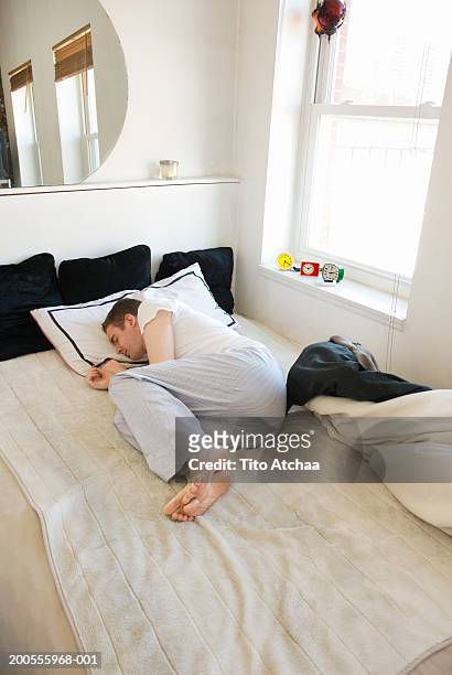 young man sleeping in bed, lying on side - position du foetus photos et images de collection