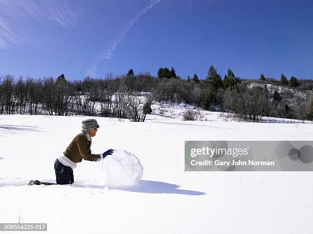 young woman rolling large snowball, side view - snowball stock pictures, royalty-free photos & images