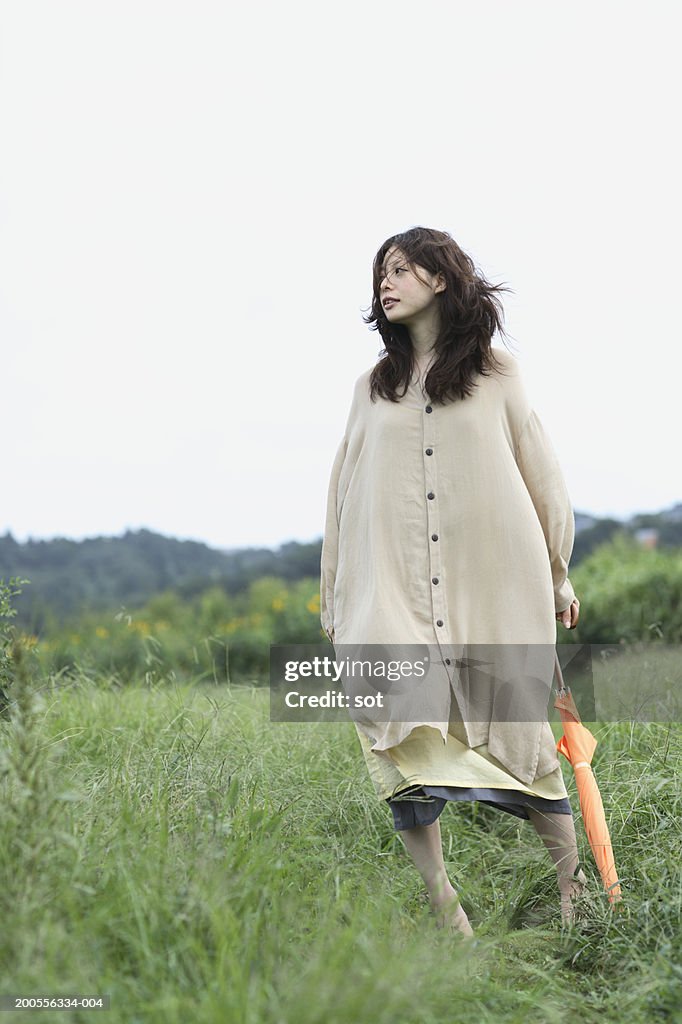 Young woman with umbrella standing in field